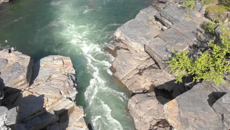 Wild-river-rapid-flow-through-eroded-Bedrock-on-a-sunny-day---Crane-down-shot