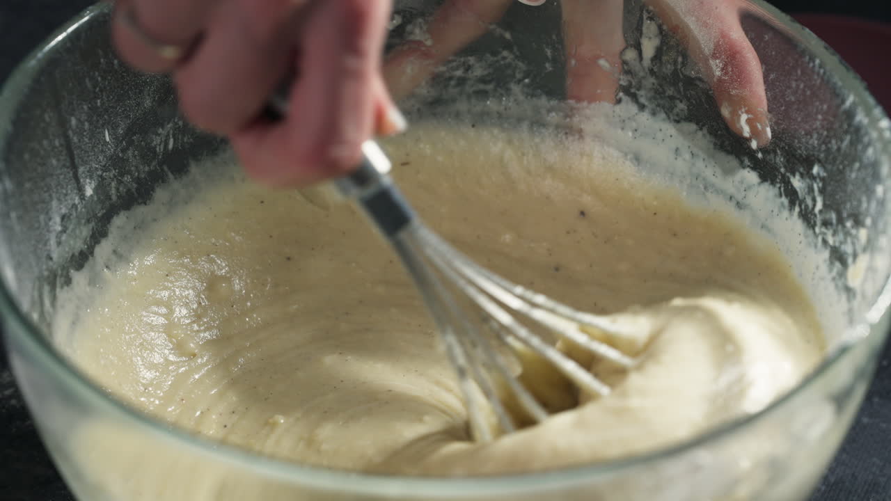Scooping cupcake batter using whisk to continue to remove lumps with precision for baking, top down slow motion