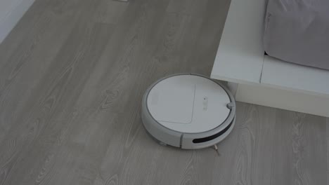 Weißer-Roboterstaubsauger-Auf-Laminatboden,-Der-Staub-Im-Wohnzimmer-Reinigt.-Intelligente-Housekeeping-Technologie.