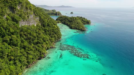 Vuelo-Cinematográfico-De-Drones-Junto-A-La-Montaña-De-La-Isla-Con-Buceadores-En-El-Agua.