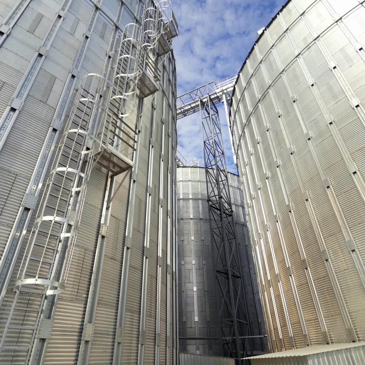 Aluminum grain elevators. Agricultural equipment for storing harvest. Modern warehouse. Granary in a sunny day. Close-up.