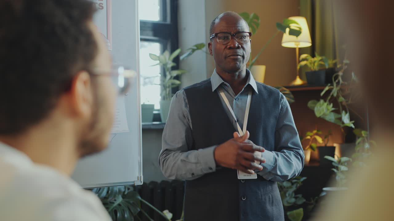 Senior Black Teacher Giving Class to Immigrant Students in School