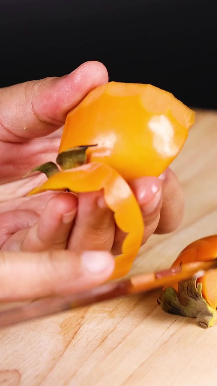 Hands skillfully peeling a ripe persimmon