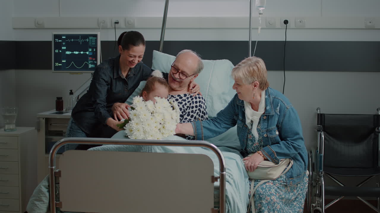 Senior man receiving visit from mother and little girl in hospital ward