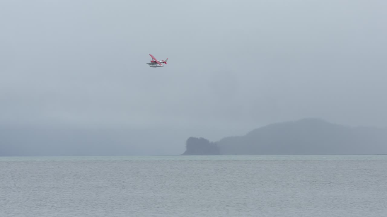 안개 낀 아침에 알래스카의 피요르드 상공을 비행하는 플로트 비행기
