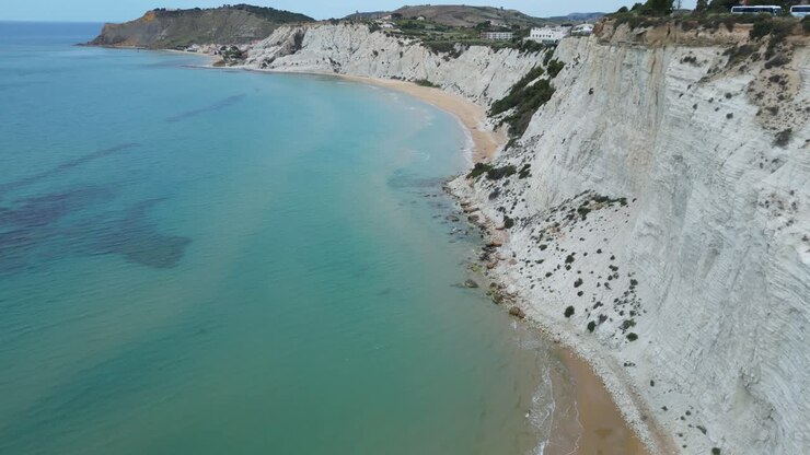 Filmato aereo con drone della Scala dei Turchi, Sicilia: scogliere di marna bianca che scendono nel mare turchese, onde costiere e drammatica luce mediterranea. Ideale per progetti di viaggio, naturalistici e legati al patrimonio culturale.