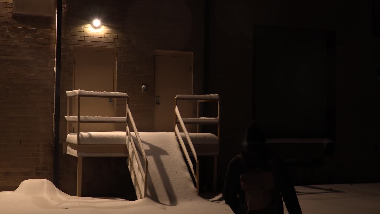 밤 에  비어 있는 로딩 도크 로 눈 을 걸어가는 젊은 성인 남성