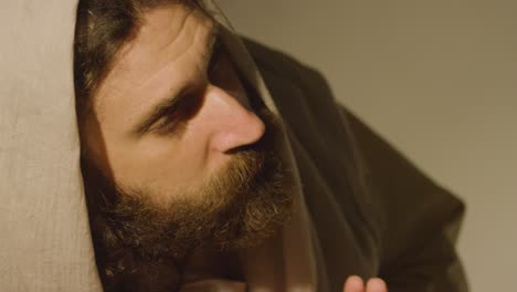 Man Wearing Robes With Long Hair And Beard Representing Figure Of Jesus Christ Looking Up And Praying