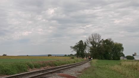 an diesel locomotive traveling by its self thru the countryside on a cloudy fall day