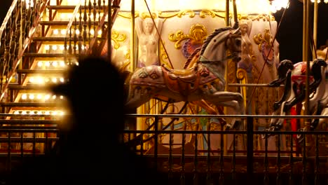 horses inside moving carousel, roundabout or merry-go-round surround with colorful lights