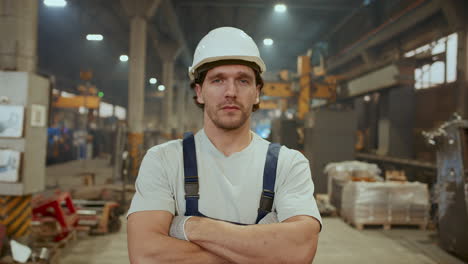 portrait of confident worker posing with crossed arms in industrial factory