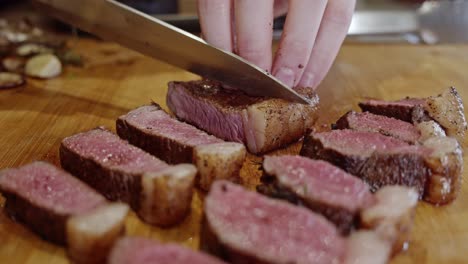 cortar bistec frito en pedazos en una tabla cortada de madera con un cuchillo de acero