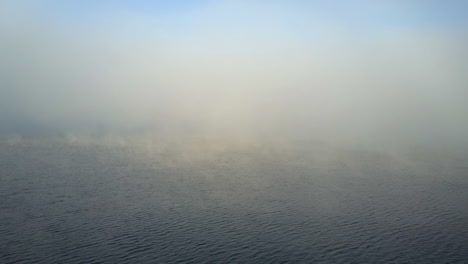 Aerial:-Thick-fog-rises-from-surface-of-warm-lake-on-cool-morning