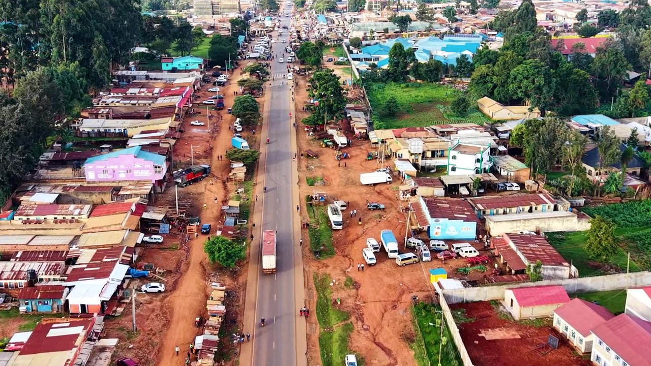 Strade del Kenya, strade rurali, insediamento rurale povero, strada danneggiata con drone che riprende veicoli sulla strada dall'alto