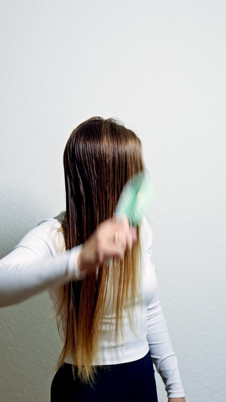 Beautiful healthy hair after cosmetic procedures. Smiling beautiful woman combing long shiny hair with comb in the morning. Hair care