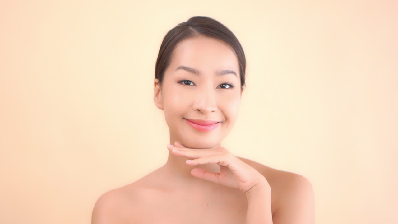 아름다운 젊은 아시아 여성의 클로즈업은 그녀의 결점 없는 피부를 과시합니다