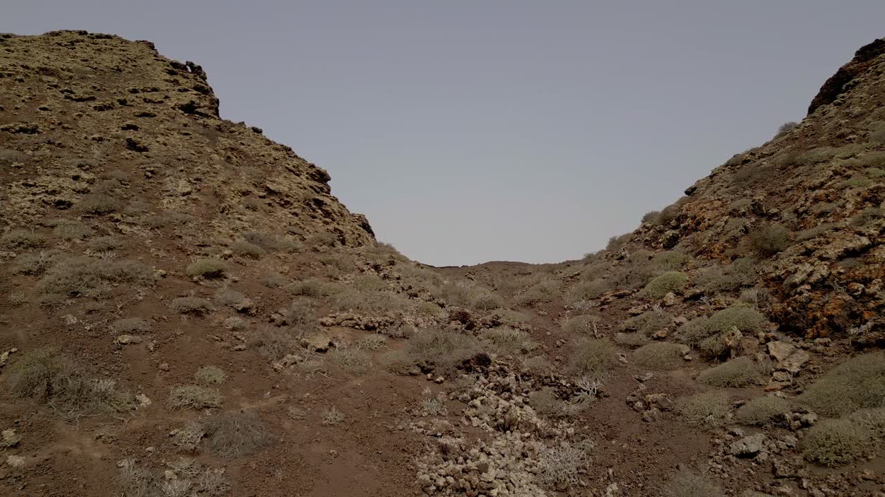 Low-altitude flight towards the entrance to the volcano crater. People descending from a volcano crater. Lanzarote. Canary Islands.