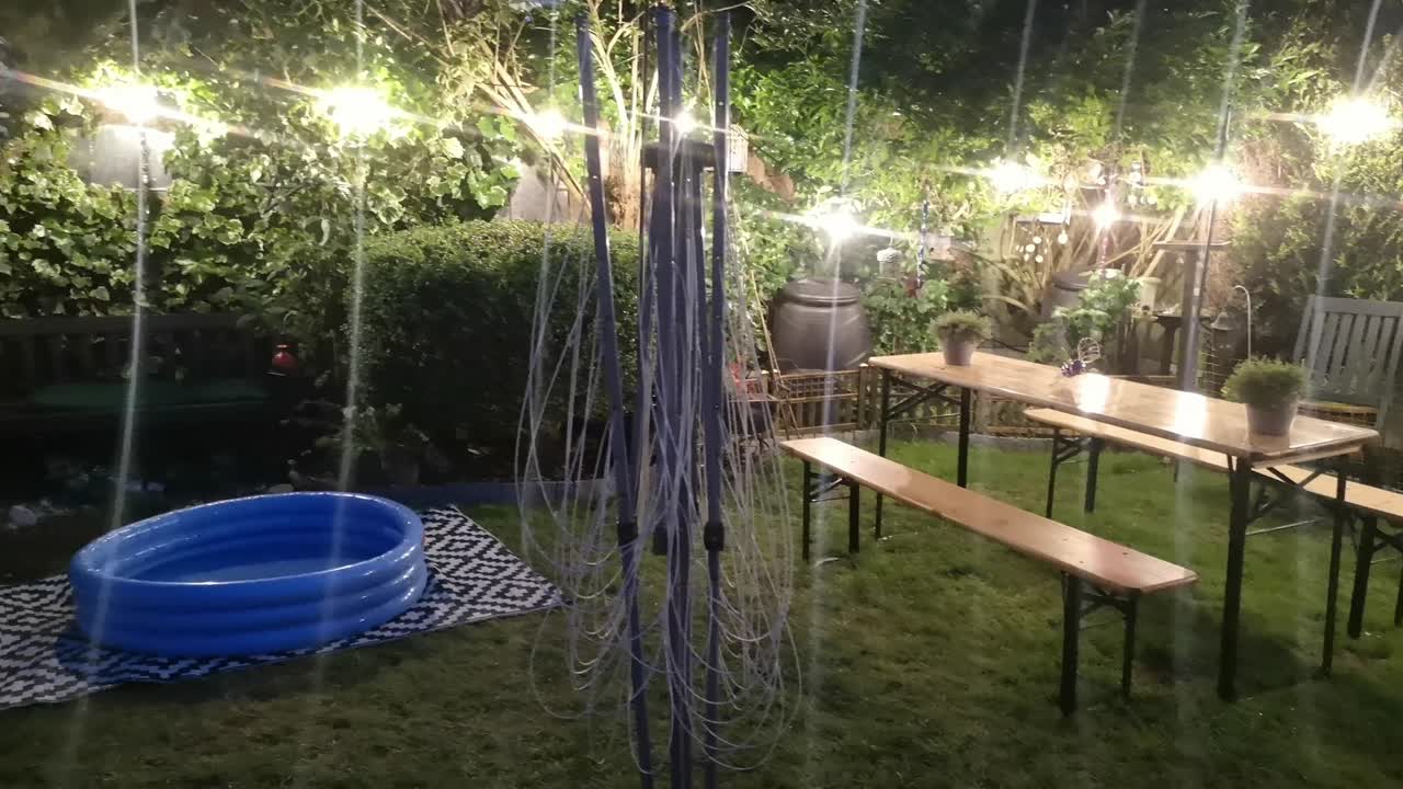 반 ⁇ 이는 조명된 현대 교외 야간 정원, 덤불 주위의 반 ⁇ 이는 스트링 조명으로 장식되어 있습니다.