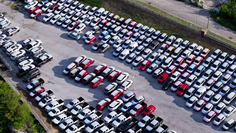 Transport-lot-full-of-white-roofed-cars-packed-tightly-off-side-of-highway