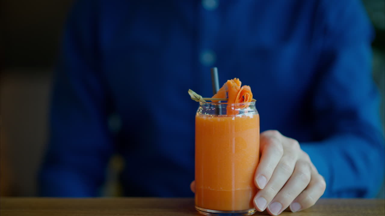 Uomo che beve succo di carota con una cannuccia in un ristorante