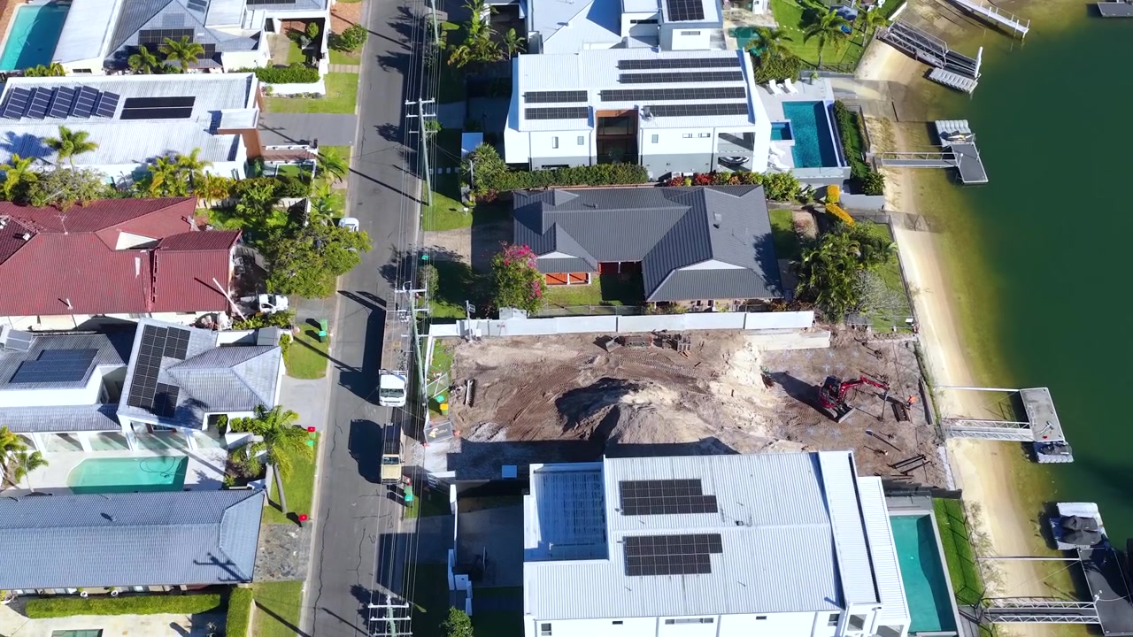 Aerial drone shot of residential construction site and luxury waterfront houses in Broadbeach Waters, Australia.