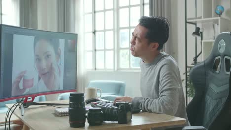 Asian Cameraman In Long Sleeved T-Shirt Having Backache While Using Desktop Computer For Working At Home.