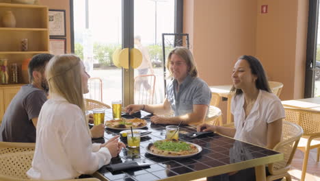 group of friends sitting at a restaurant table while they drink and talk to each other