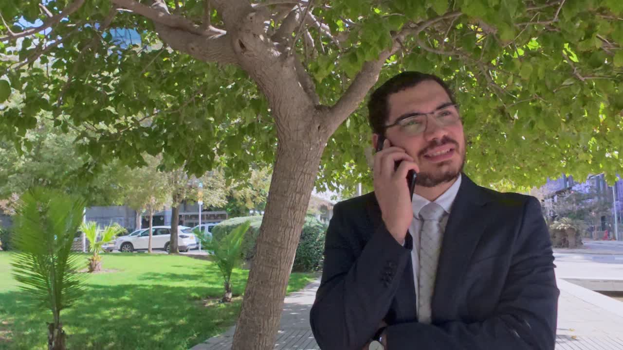 Empresario serio con el teléfono esperando en un parque de la ciudad
