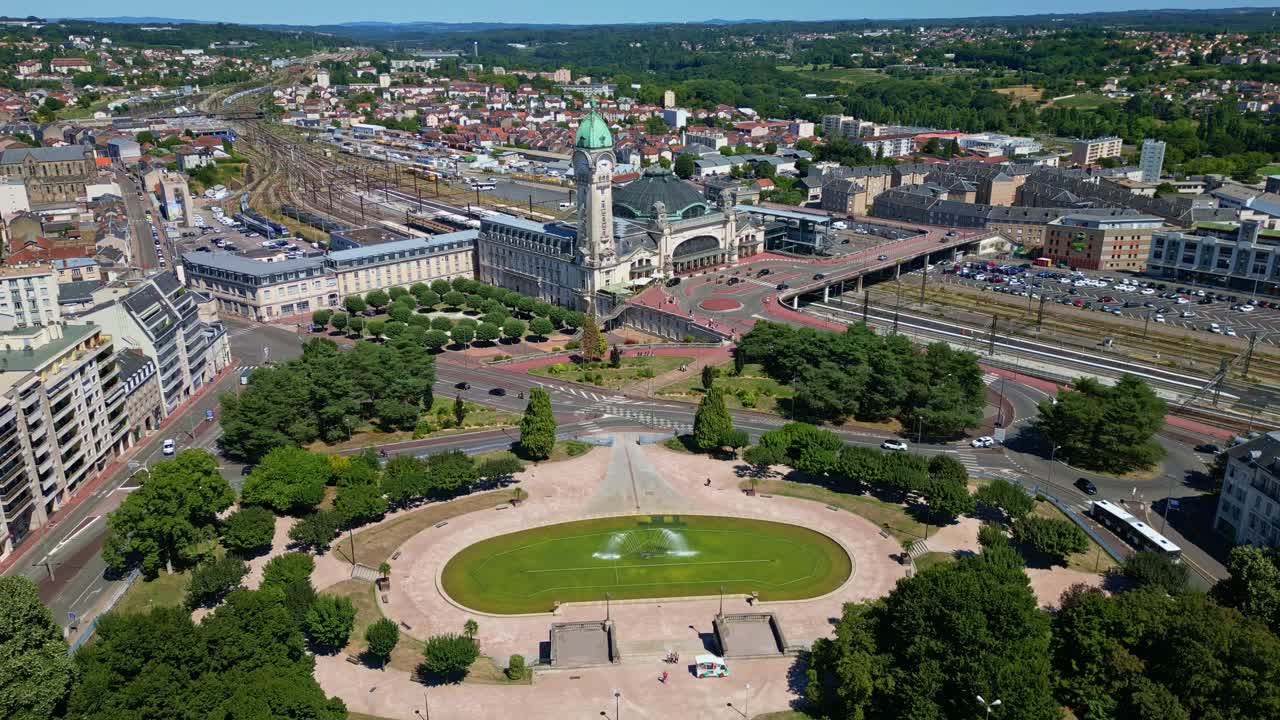 Drone shot with a gentle movement over the Gare de Limoges and Champ de Juillet, showing the station, tracks, traffic, and cityscape on a sunny day - France