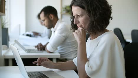 side view of focused caucasian woman typing on laptop