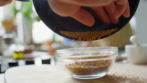 putting toasted sesame seeds in bowl
