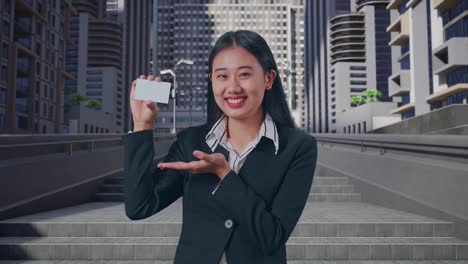 도시 에서 서 있는 동안 손 에  카드 를 추천 하는 미소 를 가진 아시아 의 사업가