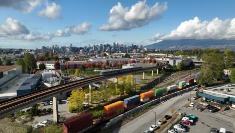 skytrain moving on railway passing by marshalling yard in false creek flats, vancouver, canada