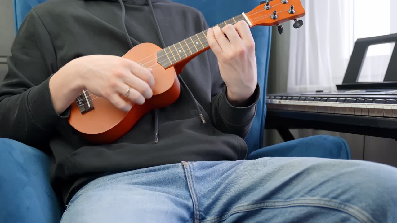 Musician practicing ukulele, close up view