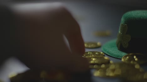 studio shot of green leprechaun top hat and hand collecting gold coins to celebrate st patricks day