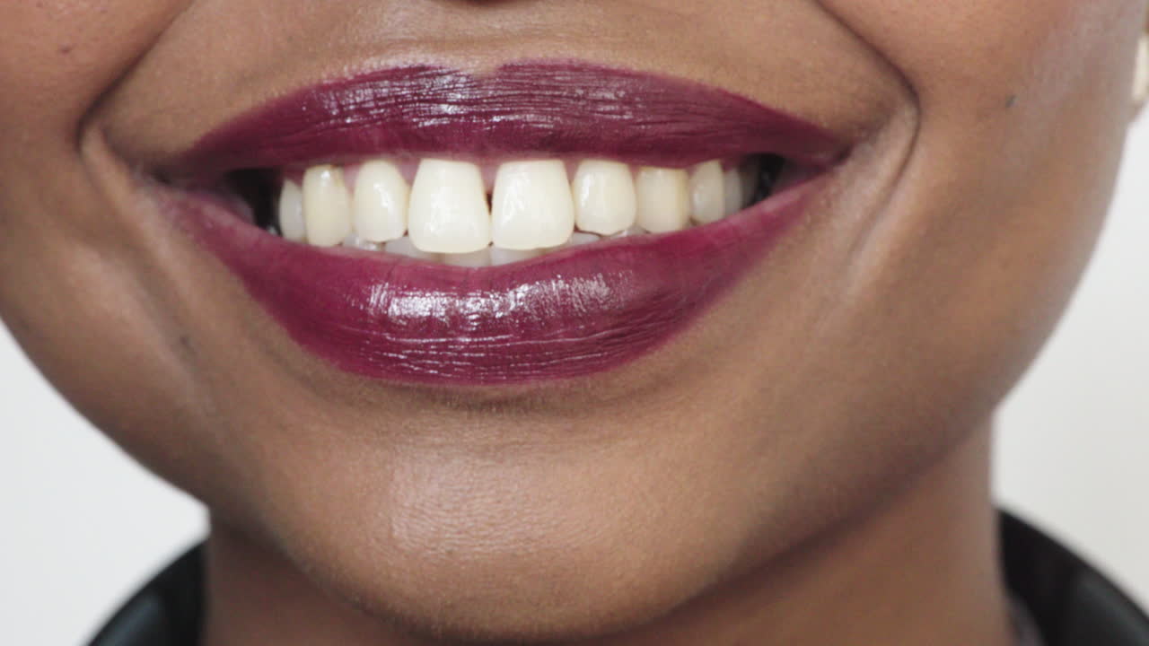 primer plano de una mujer afroamericana labios brillantes sonriendo feliz mostrando dientes sanos hermosa piel perfecta