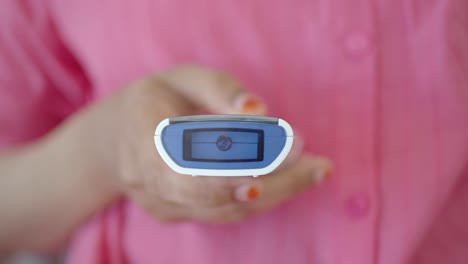 primer plano de una persona que utiliza un termómetro digital para comprobar su temperatura