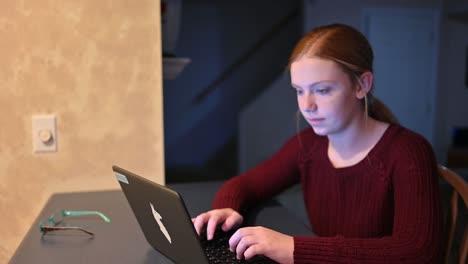 A-young-teenager-is-typing-on-a-laptop-and-looks-up-at-the-camera-to-give-an-inquisitive-look-while-web-surfing