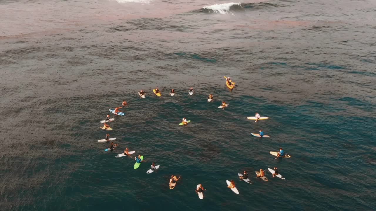 AERIAL SLOWMO: Group of surfers forming a circle on the sea in a funeral's ceremony in Canary Islands