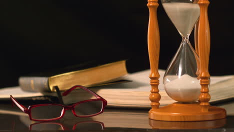 reading glasses falling beside hourglass and bible