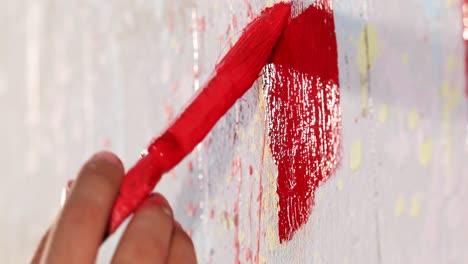 a man is painting a wall in red color with brush, close up shot, insert shot