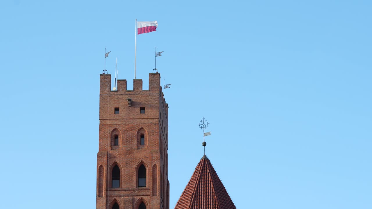 Malbork Castle tower with big Polish flag, waving in the wind