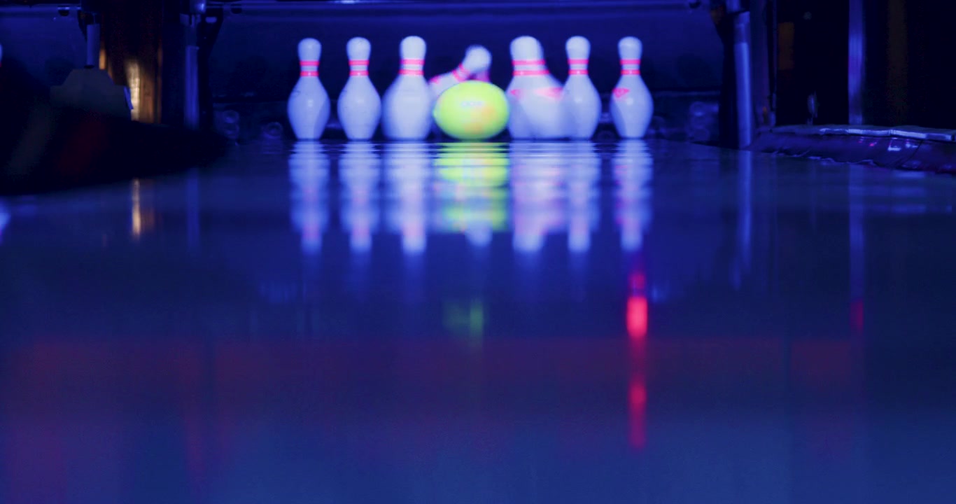 The bowler confidently throws the ball, striking a perfect strike.All ten pins go flying in different directions, leaving a clean slate behind—a triumphant strike for the skilled bowler.