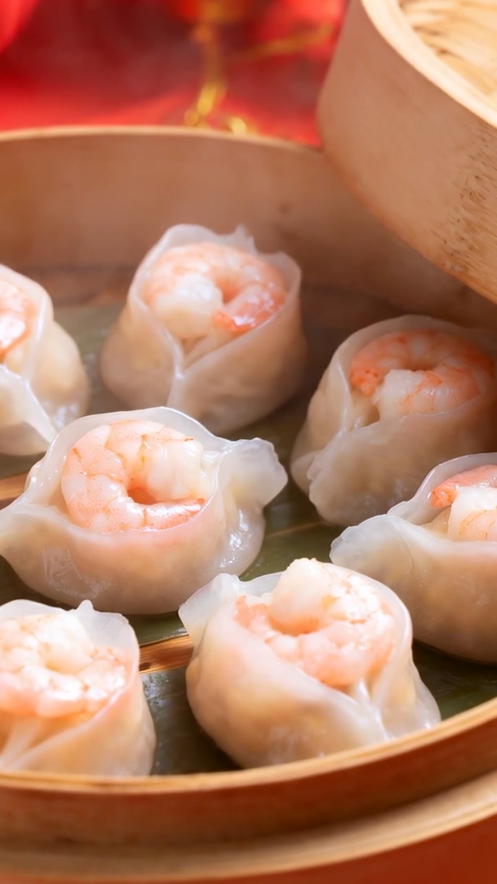 Vertical video: Releasing steam, shrimp dumplings resting in bamboo steamer for serving, red cloth
