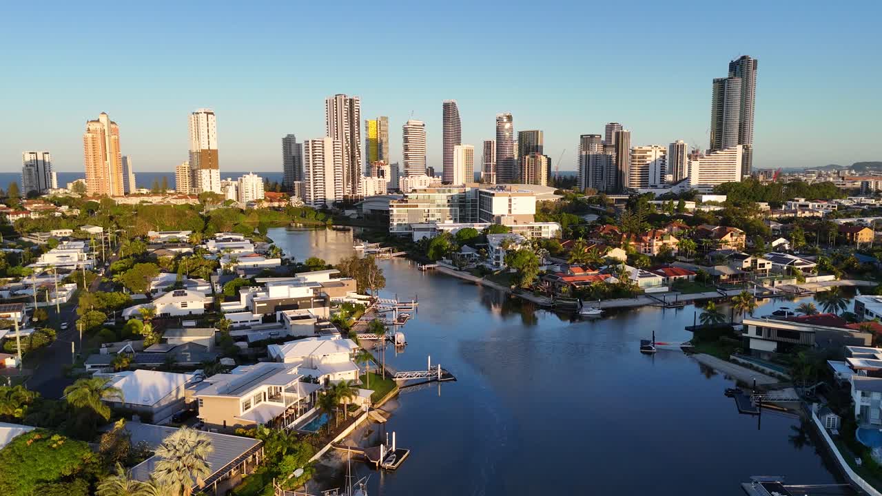 Drone footage captures Gold Coast's skyline and waterways at sunset, highlighting urban architecture and serene water reflections