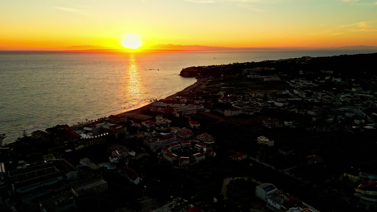 Ripresa aerea in avanti con drone dell'alba su una città lungo la costa ad Atene, Grecia, al mattino.
