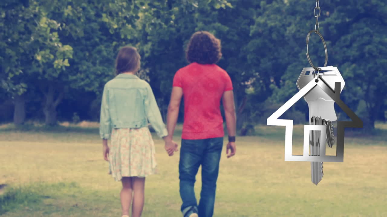 llaves de la casa y llaves colgando con una pareja caminando en el fondo