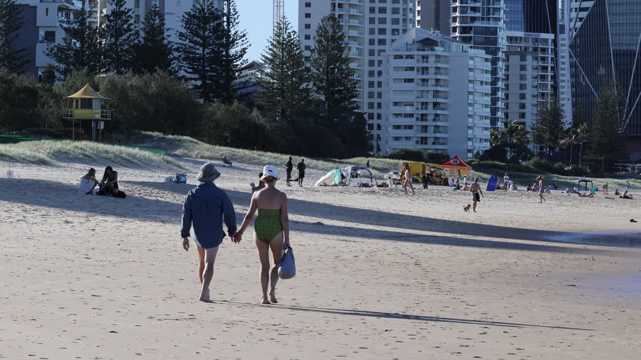 노인 부부는 이 나는 해변을 따라 산책합니다.