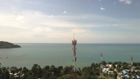 aerial orbit shot of telecommunications tower on a tropical island with ocean