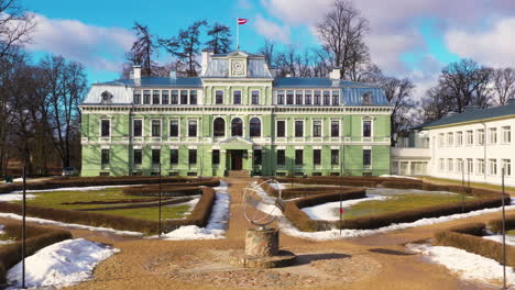 Snow-covered-Kokmuiza-castle-park-grounds-with-manicured-lawn-shrubs